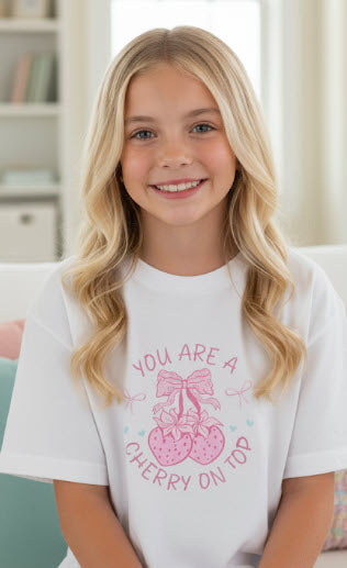 Young girl wearing a white t-shirt with a pink graphic and text.
